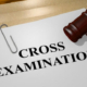 3D rendering of a gavel sitting on a piece of paper stating "Cross Examination" in large block letters